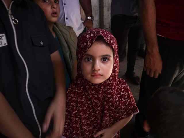 En flicka från Palestina står bland folk och tittar in i kameran. 