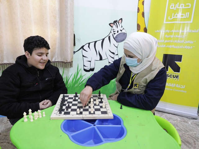 En pojke som heter Maher sitter på ett av RESCUE:s center och spelar schack med en medarbetare.