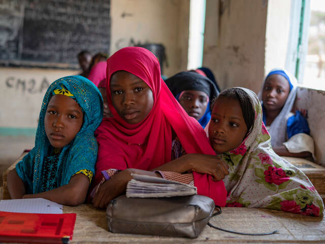 Maryama och hennes klasskompisar sitter vid ett bord i ett klassrum i Niger.