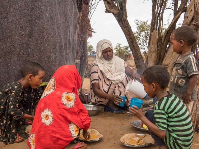 Bisharo feeds her ten children a common Somali breakfast, Buls, a dish made of cooked peas spread on injera bread.