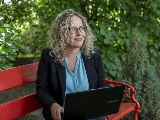 Justyna in her garden, working at her laptop.