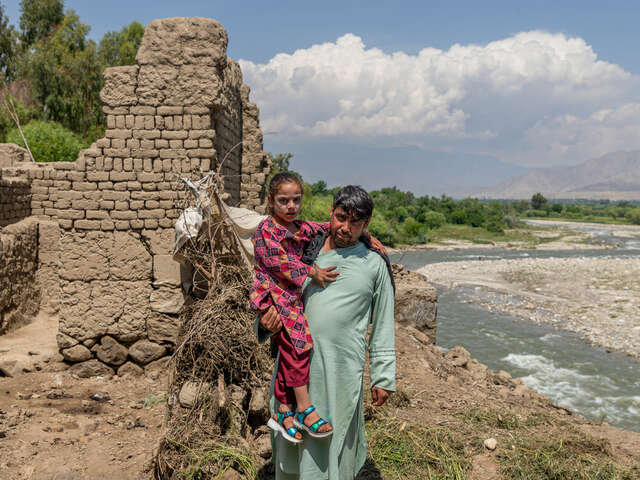 Pappa och dotter i Afghanistan står vid familjens hem som förstörts översvämningar. 