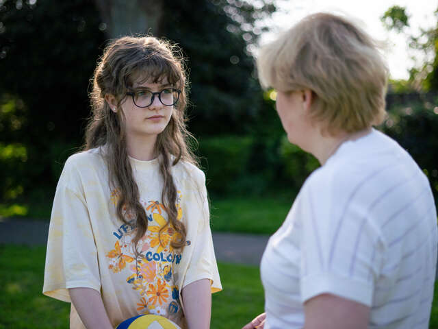 Tonårsflicka och mamma i trädgården till sitt nya hem i England, dit de flytt från Ukraina.