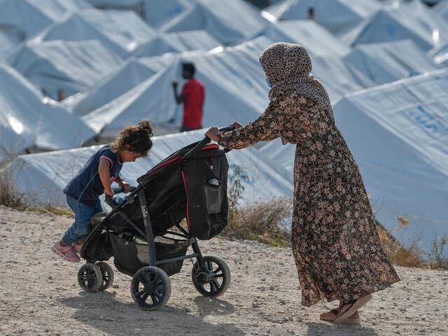 En kvinna drar en barnvagn vid ett flyktingläger på Lesbos, Grekland.
