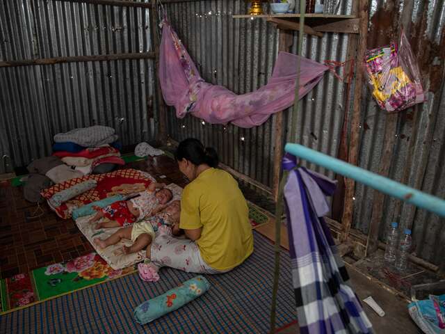 Nwe looks at her twins in bed.