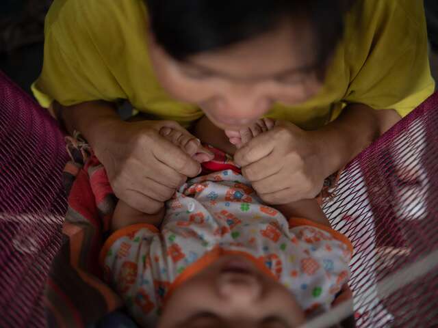 Nwe plays with her child.