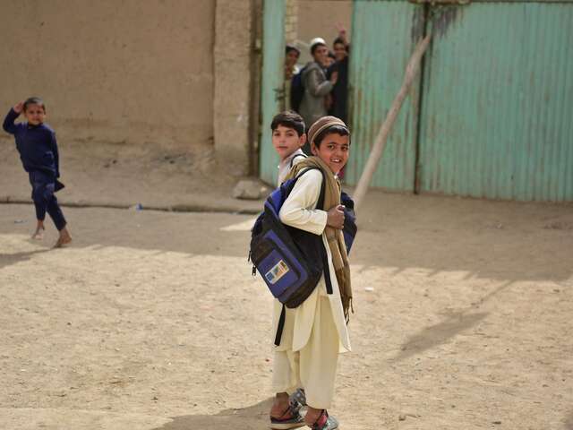 Children about to enter the learning center, looking and smiling at the camera