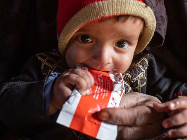 Ett litet barn äter nötkräm från en klämmis-förpackning. 