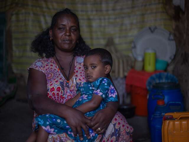 En mamma håller sin dotter i knät i sitt hem i Tigray, Etiopien.
