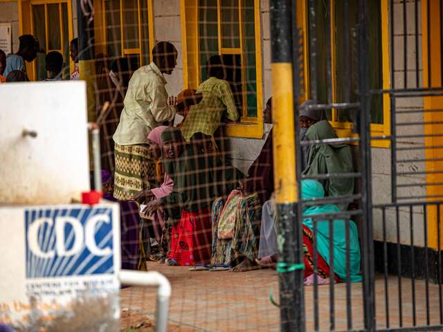 We see people seated and standing, waiting for their turn at a medical centre in Kenya.