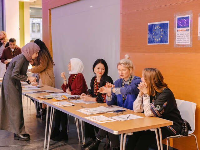 Fyra RESCUE-arbetare sitter bakom en informationsdisk och pratar med klienter i England.