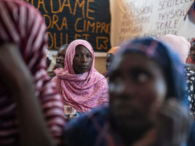 En kvinna i Tchad sitter i en samling med andra kvinnor och kollar in i kameran.