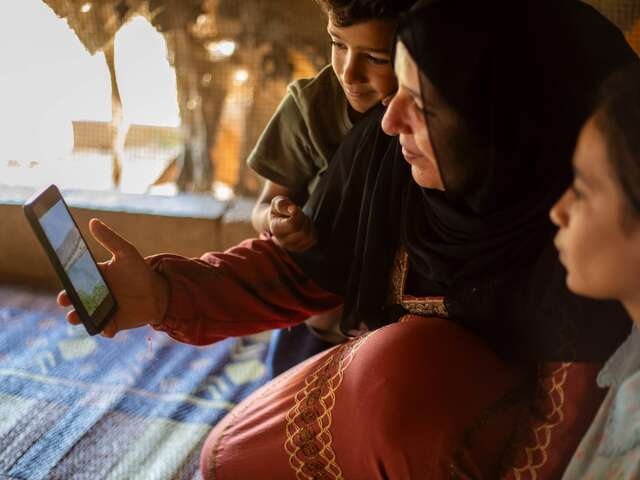 Halima zeigt ihren Kindern ein Video von ihrem Dorf in Syrien.