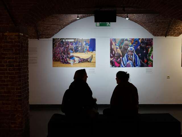 Silhouettes of people seated looking at the exhibition. 