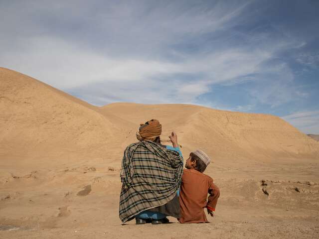 Abdul Haq outside with his oldest son Naqib Ullah as they talk about their village mountains in Afghanistan.