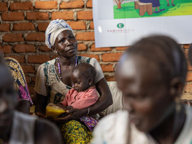 En kvinna i ett flyktingläger i Uganda håller sitt barn under en workshop.
