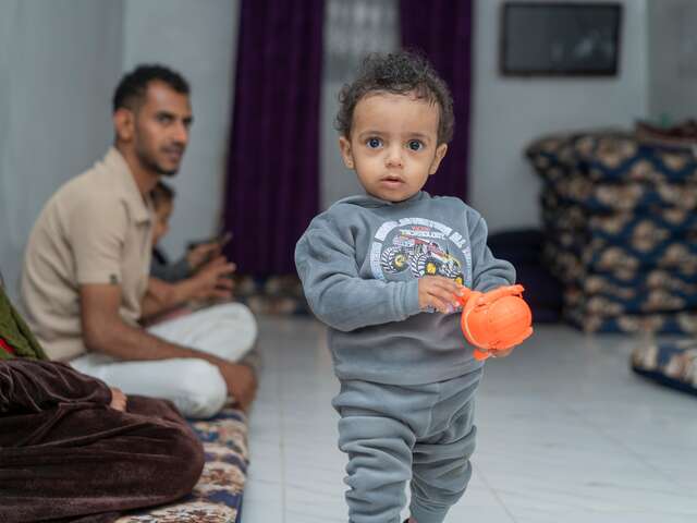 One-year-old Aws plays with a toy at home, surrounded by his father, Nader and his family. 