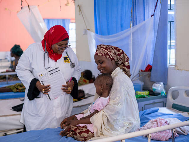 Läkaren Ummi undersöker lila Aisha som sitter i mamma Hauwas knä.