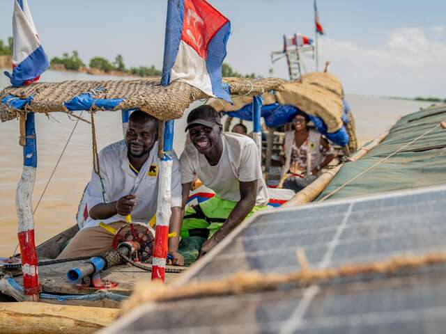 Two men from IRC staff smiling from a boat 
