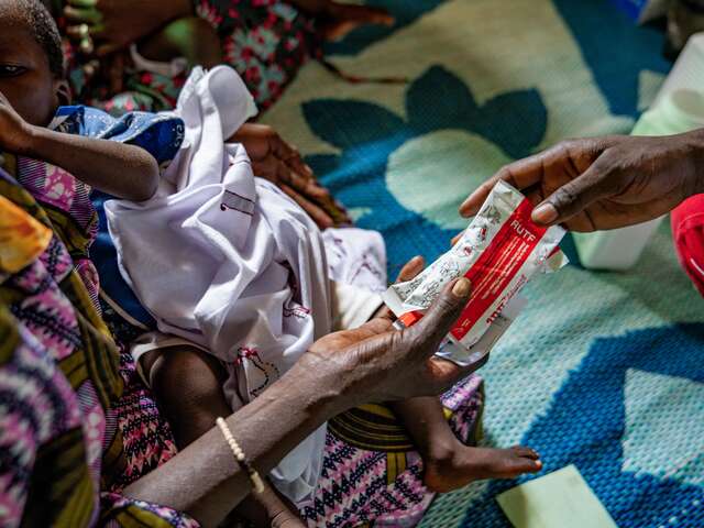 IRC staff providing food packets to a mother and her child 