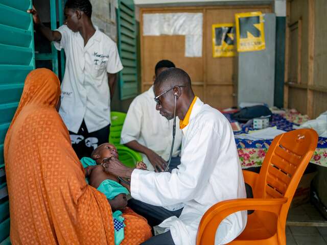 Doctor checking the heartbeat of a baby on his mom's laps