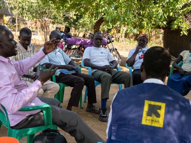 A village health team member leads a community meeting, sharing disease prevention tips with local residents.