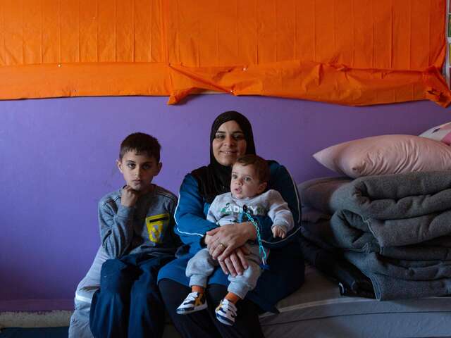 Warda holds her baby, Mohammad, in her lap. Her other son, Wissam, sits next to them on a small mattress.