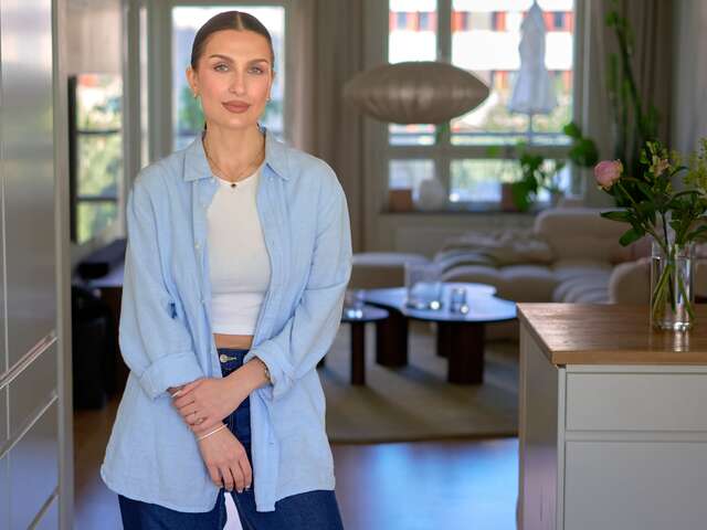 Meira Omar står i sitt hem och ler mot kameran