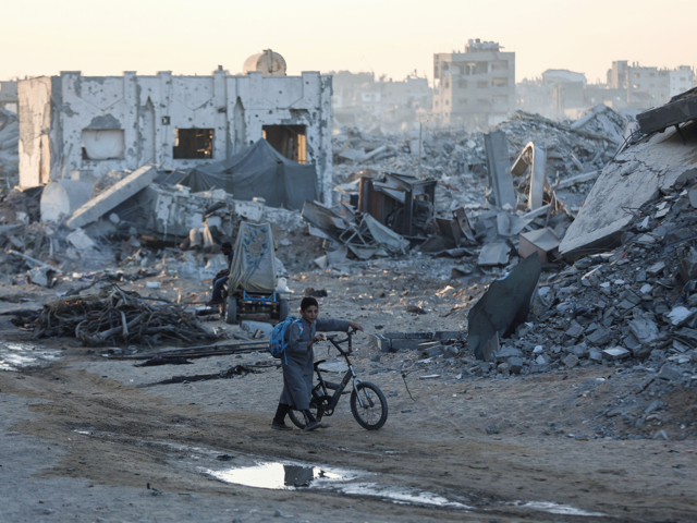 Ein Junge schiebt sein Fahrrad an den Ruinen zerstörter Gebäude im Stadtviertel Sheikh Radwan in Gaza-Stadt vorbei, aufgenommen am 22. Oktober 2025.