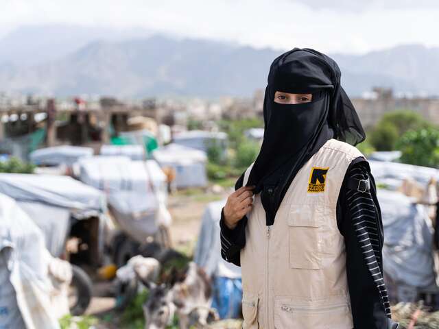 Dr Saiham in front of a displacement camp, looking at the camera