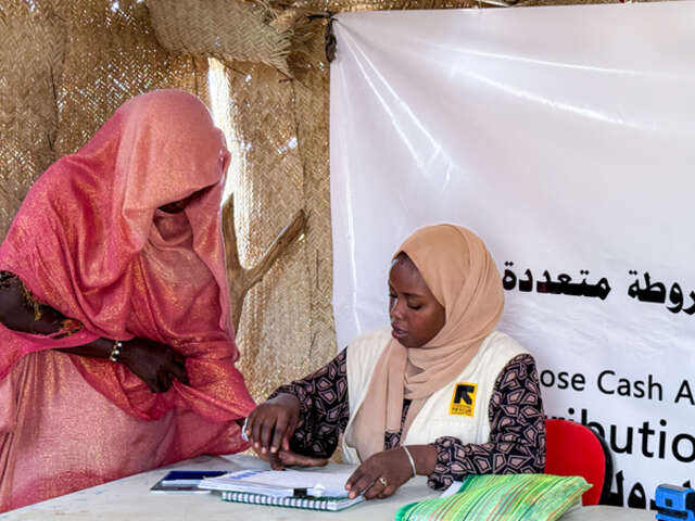 Hawa registers for cash assistance with IRC's Economic Recovery and Development Assistant Hasna.