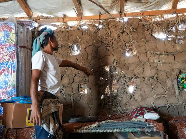 Ahmed shows us the inside of his makeshift shelter, built from mud and wood.