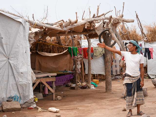 Ahmed points to the makeshift shelter he has built for his family. He wishes to move his family into a more secure home soon.