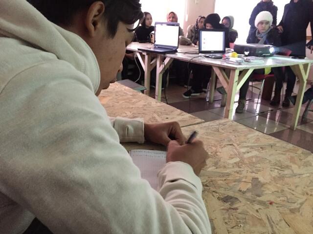 A boy writes an assignment at his desk in an English class for refugee children in Belgrade.