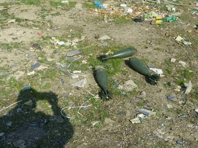 Explosives left in the grass with the nearby shadow of the person photographing them. 