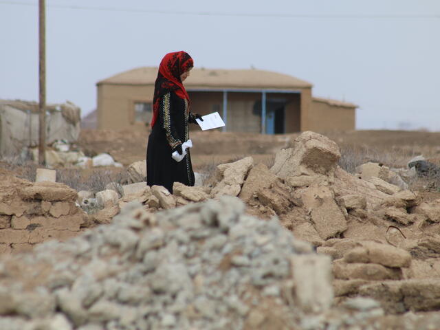 A woman picks her way through rubble in a village in rural, northeastern Syria that has been heavily damaged during the war.