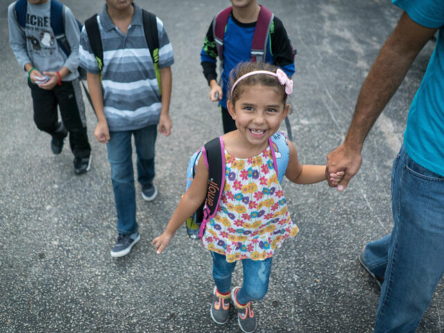 5-year-old Jori walks to school holding her father's hand