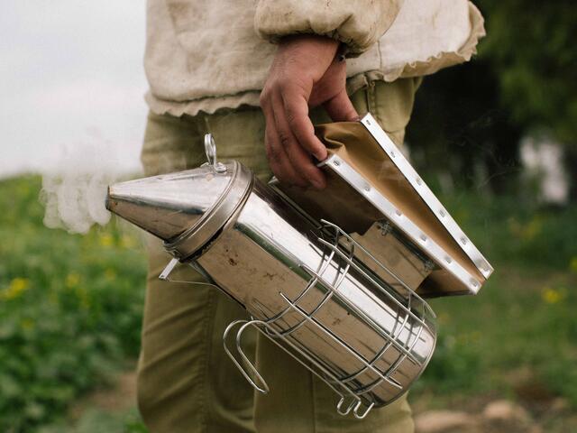 Hudaifah holds the smoker used to calm the bees so he can collect honey.