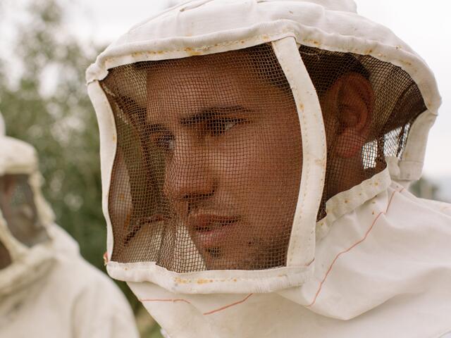 Close-up shot of Hudaifah's face, wearing a beekeeping suit.