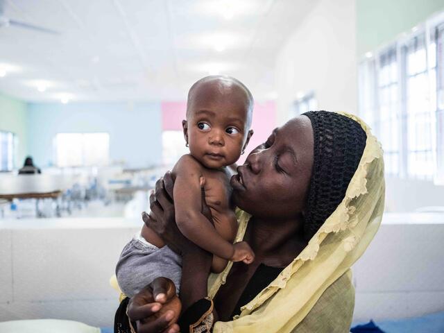 Amma cradles her daughter Kaka in her arms at the IRC's clinic in northeast Nigeria.