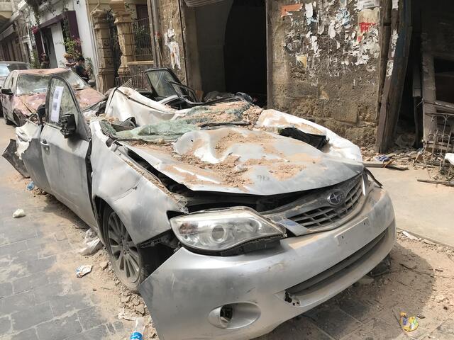 A broken down car, crushed and covered in dust.