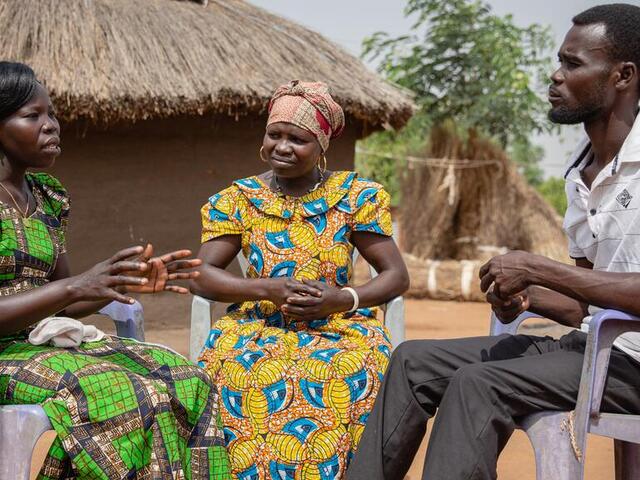 Two women and a man sit in a circle and share a conversation.