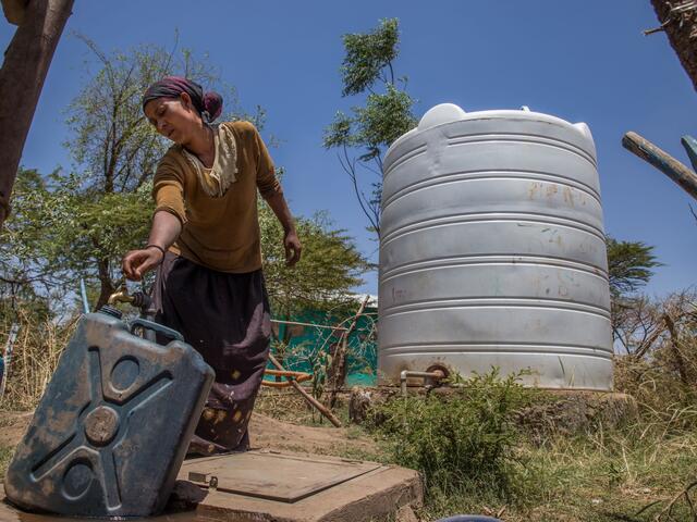 Woman filling a bucket with water from a tap