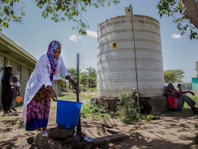 Woman filling a bucket with water from a tap