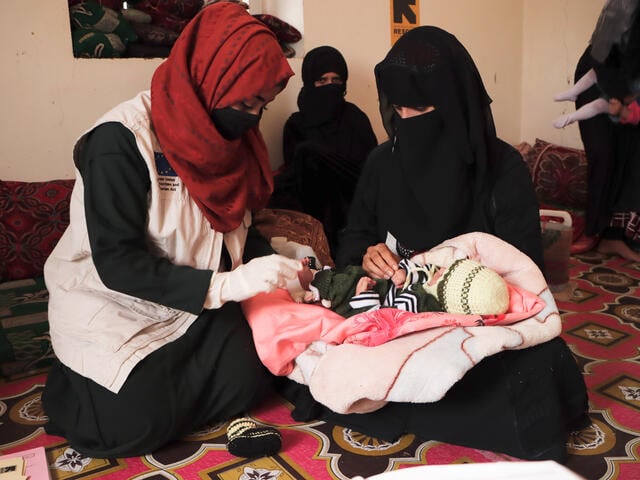 Bushra examining an infant being held by its mother