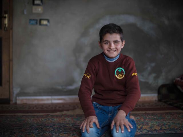 10-year-old Ali is kneeling and smiling at the camera.