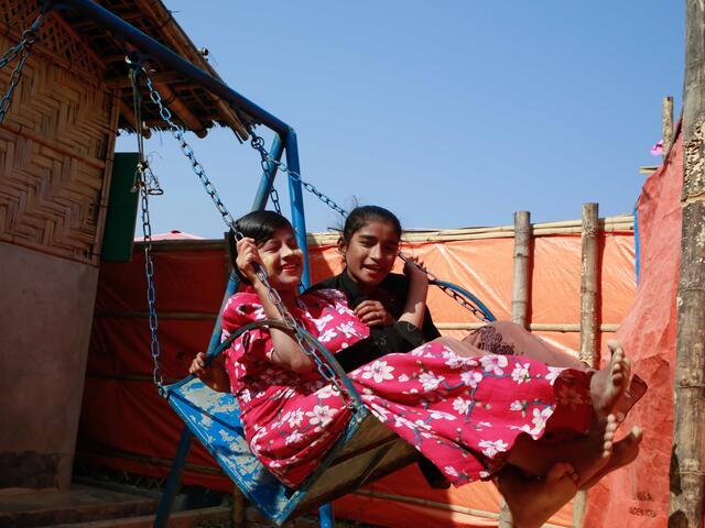 Two girls play on a swing outside the IRC's Women's Centre in Teknaf refugee camp in Bangladesh.