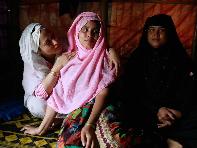 Razia Sultana visits a Rohingya family in Ukhiya camp. Three women sit together on the floor of a home.