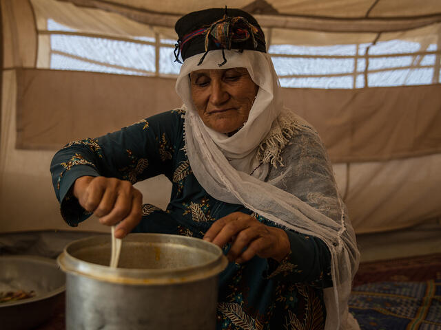 A woman cooks over a small steel pot.