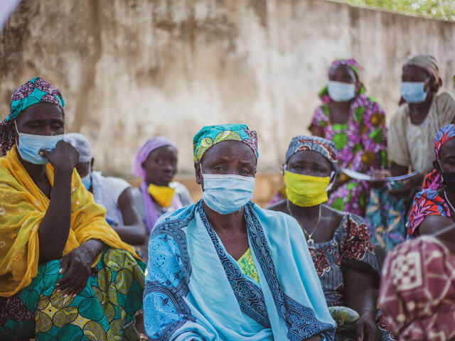 Women sat around wearing masks.